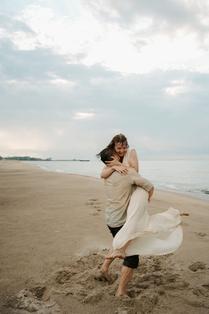 couple spinning on beach in the rain