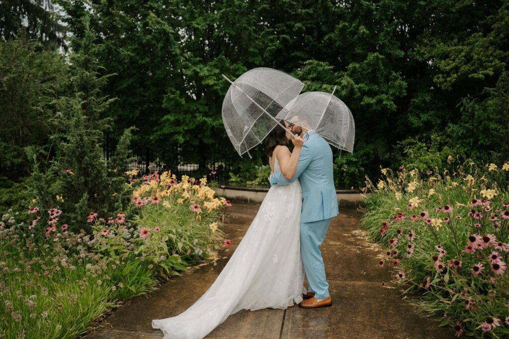 couple kissing under umbrellas during first look
